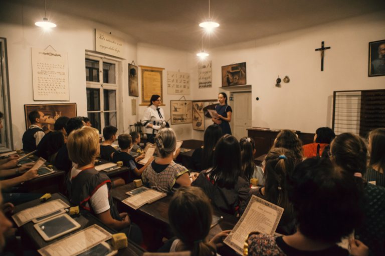 Učenci v učilnici ter gospodična učiteljica