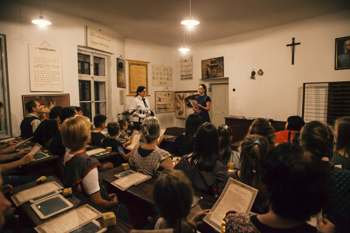 Učenci v učilnici ter gospodična učiteljica
